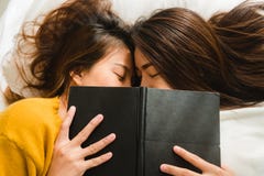 Vue supérieure de baiser heureux lesbien et du sourire de couples de belles jeunes femmes asiatiques tout en se situant ensemble Photo libre de droits Vue supérieure de baiser heureux lesbien et du sourire de couples de belles jeunes femmes asiatiques tout en se situant ensemble Photo libre de droits