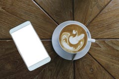 Vue supérieure de style d'art de latte de café dans la tasse en céramique blanche sans compter que le téléphone intelligent blanc photographie stock libre de droits Vue supérieure de style d'art de latte de café dans la tasse en céramique blanche sans compter que le téléphone intelligent blanc photographie stock libre de droits