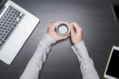 Vue supérieure des mains masculines tenant une tasse de café avec l'ordinateur portable, le comprimé et le téléphone intelligent Photos stock Vue supérieure des mains masculines tenant une tasse de café avec l'ordinateur portable, le comprimé et le téléphone intelligent Photos stock