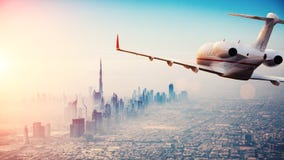 Vuelo del avión de reacción privada sobre la ciudad de Dubai en li hermoso de la puesta del sol fotografía de archivo Vuelo del avión de reacción privada sobre la ciudad de Dubai en li hermoso de la puesta del sol fotografía de archivo