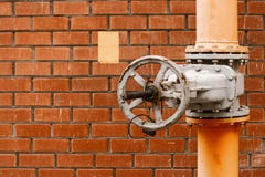Válvula de gas en el tubo industrial de la distribución amarilla del gas natural delante de la pared de ladrillo roja con el copy Imagenes de archivo