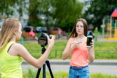 vänflicka två Sommar i natur Rekord- video på kameran I hans händer rymmer en smartphone Begreppet av barn royaltyfri foto vänflicka två Sommar i natur Rekord- video på kameran I hans händer rymmer en smartphone Begreppet av barn royaltyfri foto