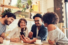 Vänner i ett kafé som ser fotona på mobiltelefonen arkivfoto Vänner i ett kafé som ser fotona på mobiltelefonen arkivfoto