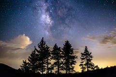Vía láctea sobre las nubes y los árboles de pino imagen de archivo Vía láctea sobre las nubes y los árboles de pino imagen de archivo