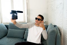 Vídeo feliz novo da gravação do blogger na câmera para o polegar da exibição do blogue do Internet acima foto de stock Vídeo feliz novo da gravação do blogger na câmera para o polegar da exibição do blogue do Internet acima foto de stock