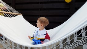 vídeo 4k del niño pequeño feliz sonriente que se sienta en hamaca en el patio trasero almacen de metraje de vídeo vídeo 4k del niño pequeño feliz sonriente que se sienta en hamaca en el patio trasero almacen de metraje de vídeo