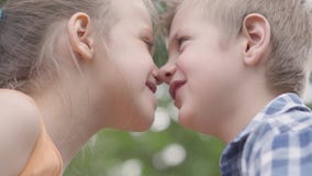 W górę portreta śliczny chłopiec i dziewczyny obsiadanie w parku, próbujący nacierać ich nosy i mieć zabawę Kilka szczęśliwy zdjęcie wideo W górę portreta śliczny chłopiec i dziewczyny obsiadanie w parku, próbujący nacierać ich nosy i mieć zabawę Kilka szczęśliwy zdjęcie wideo