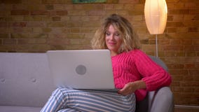 W górę strzału gospodyni domowa w różowym pulowerze ma wideo wzywa laptop i skinąć ono zgadzać się w domowej atmosferze zbiory W górę strzału gospodyni domowa w różowym pulowerze ma wideo wzywa laptop i skinąć ono zgadzać się w domowej atmosferze zbiory