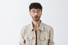 Waist-up shot of amazed and surprised emotive adult bearded guy in transparent glasses and beige jacket folding lips in royalty free stock photography Waist-up shot of amazed and surprised emotive adult bearded guy in transparent glasses and beige jacket folding lips in royalty free stock photography
