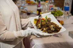 A waitress in white gloves holding a plate with a meat diet of watered brown sauce royalty free stock image A waitress in white gloves holding a plate with a meat diet of watered brown sauce royalty free stock image