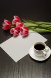 Wakacyjny pojęcie Bukiet różowi tulipany, filiżanka kawy i prześcieradło papier na czarnym drewnianym tle, Vertical rama obrazy stock Wakacyjny pojęcie Bukiet różowi tulipany, filiżanka kawy i prześcieradło papier na czarnym drewnianym tle, Vertical rama obrazy stock