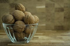 Walnut in a glass bowl on a wooden background. Side view stock photo Walnut in a glass bowl on a wooden background. Side view stock photo