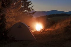 Wandelaarstent in bergen bij avond met een vuur met fonkelingen stock fotografie Wandelaarstent in bergen bij avond met een vuur met fonkelingen stock fotografie