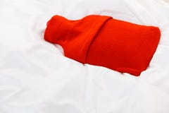 Warme roodgloeiende waterfles op wit beddegoed royalty-vrije stock afbeelding Warme roodgloeiende waterfles op wit beddegoed royalty-vrije stock afbeelding