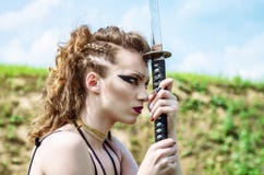 Warrior girl with Amazon make-up holds a sword