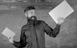 Wat u zou verkiezen Houdt leraars gebaarde hipster boek en laptop Leraar die moderne het onderwijsbenadering kiezen Document stock fotografie Wat u zou verkiezen Houdt leraars gebaarde hipster boek en laptop Leraar die moderne het onderwijsbenadering kiezen Document stock fotografie