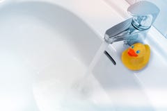 Water die van een tapkraan een witte gootsteen met een rubbereend tegenkomen royalty-vrije stock foto's Water die van een tapkraan een witte gootsteen met een rubbereend tegenkomen royalty-vrije stock foto's