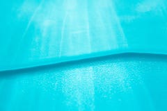 Water wave and sun rays blur abstract summer background, close-up. Blue shiny backdrop. Aqua texture