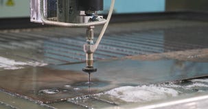 Waterjet high pressure CNC machine is cutting out a holes on a metal sheet.