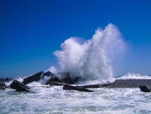 Waves breaking at the concrete breakwater on clear blue sky in a stock photography Waves breaking at the concrete breakwater on clear blue sky in a stock photography