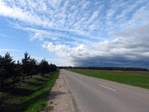 Road, trees, field and beautiful cloudy sky, Lithuania royalty free stock image Road, trees, field and beautiful cloudy sky, Lithuania royalty free stock image