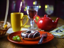 Wciąż życie z czekoladowym pączkiem na czerwonym handmade talerzu, agrestowe jagody w tle żółta filiżanka i czerwony teapot dla, zdjęcie royalty free Wciąż życie z czekoladowym pączkiem na czerwonym handmade talerzu, agrestowe jagody w tle żółta filiżanka i czerwony teapot dla, zdjęcie royalty free
