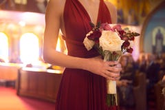 Wedding ceremony day. bridesmaid girl wearing elegant red dress holding flowers bouquet at Wedding ceremony in catholic church. royalty free stock images Wedding ceremony day. bridesmaid girl wearing elegant red dress holding flowers bouquet at Wedding ceremony in catholic church. royalty free stock images