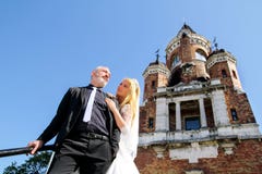 A handsome wedding couple is standing on the stairs in front of the beautiful old church. stock photo A handsome wedding couple is standing on the stairs in front of the beautiful old church. stock photo