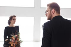 Wedding couple groom and bride posing in a white Studio. Black suit and dress. Man standing back to camera stock photos Wedding couple groom and bride posing in a white Studio. Black suit and dress. Man standing back to camera stock photos
