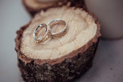 Wedding rings with beautiful carvings on the background of sawn wood and linen fabric, close-up stock images Wedding rings with beautiful carvings on the background of sawn wood and linen fabric, close-up stock images