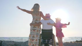 Weekend with family, invalid with pregnant woman and child raise hands, spouse in wheel chair hug wife and little girl