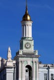 Weergeven van de oude kerk met een klok en een gouden koepel en een klokketoren, in het centrum van Kiev, tegen de blauwe hemel stock fotografie Weergeven van de oude kerk met een klok en een gouden koepel en een klokketoren, in het centrum van Kiev, tegen de blauwe hemel stock fotografie