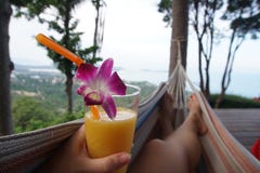 Weibliche Beine, die in der Hängematte mit Mango-Cocktail POV schwingen lizenzfreie stockfotografie Weibliche Beine, die in der Hängematte mit Mango-Cocktail POV schwingen lizenzfreie stockfotografie
