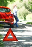 Weibliche Fahrer-Broken Down On-Land-Straße mit Warnzeichen herein F stockbild Weibliche Fahrer-Broken Down On-Land-Straße mit Warnzeichen herein F stockbild