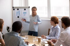 Weibliche Gesch?ftstrainerstellung nahe dem whiteboard, das mit verschiedenem Team spricht lizenzfreies stockbild Weibliche Gesch?ftstrainerstellung nahe dem whiteboard, das mit verschiedenem Team spricht lizenzfreies stockbild