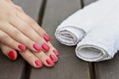 Weibliche Hände mit einer roten Maniküre und weißen Tüchern auf einem hölzernen lizenzfreies stockbild Weibliche Hände mit einer roten Maniküre und weißen Tüchern auf einem hölzernen lizenzfreies stockbild