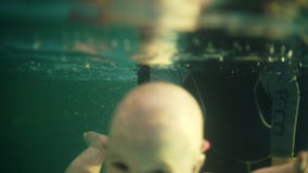 Weiblicher Trainer oder Mutter unterrichten ein wenig todler, um unter dem Wasser zu tauchen H?lt ihn ?ber dem Wasser, durchn??t Weiblicher Trainer oder Mutter unterrichten ein wenig todler, um unter dem Wasser zu tauchen H?lt ihn ?ber dem Wasser, durchn??t