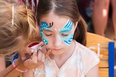 Weibliches Kindergesichtsmalerei, Schmetterlingsprozeß machend lizenzfreie stockfotografie Weibliches Kindergesichtsmalerei, Schmetterlingsprozeß machend lizenzfreie stockfotografie