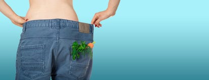 Weight loss and healthy eating or dieting concept. Slim girl in oversized jeans with a carrot, dill and parsley in the pocket. stock photo Weight loss and healthy eating or dieting concept. Slim girl in oversized jeans with a carrot, dill and parsley in the pocket. stock photo