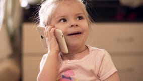 Weinig babymeisje die met telefoon binnen spelen UHD-schot stock videobeelden Weinig babymeisje die met telefoon binnen spelen UHD-schot stock videobeelden