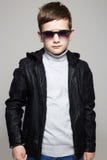 Weinig jongen in zonnebril modieus jong geitje in leer stock foto Weinig jongen in zonnebril modieus jong geitje in leer stock foto