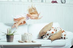 Weinig leuk blonde Noors meisje die op bank met hoofdkussens spelen, gek alleen huis, het concept van levensstijlmensen stock foto Weinig leuk blonde Noors meisje die op bank met hoofdkussens spelen, gek alleen huis, het concept van levensstijlmensen stock foto