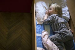 Weinig leuke peinzende blondejongen die in bed liggen stock fotografie Weinig leuke peinzende blondejongen die in bed liggen stock fotografie