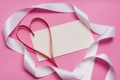 Weiße Karte mit mit Kopienraum, einem roten selbst gemachten Papierherzen und einem weißen Band auf einem rosa Hintergrund Symbol lizenzfreies stockbild Weiße Karte mit mit Kopienraum, einem roten selbst gemachten Papierherzen und einem weißen Band auf einem rosa Hintergrund Symbol lizenzfreies stockbild