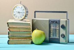 Wekker op stapel oude boeken, radioontvanger, appel op een blauwe houten lijst Retro stilleven stock foto Wekker op stapel oude boeken, radioontvanger, appel op een blauwe houten lijst Retro stilleven stock foto