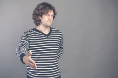 Welcome, nice to see you. Man in black and white striped sweater looking at camera with reaching out his hand offering royalty free stock photo Welcome, nice to see you. Man in black and white striped sweater looking at camera with reaching out his hand offering royalty free stock photo