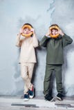 Wenig Doppeljungen, die vom Werden ein Raumfahrer spielen und träumen Porträt von lustigen Kindern mit Bageln auf grauer Wand lizenzfreie stockfotografie Wenig Doppeljungen, die vom Werden ein Raumfahrer spielen und träumen Porträt von lustigen Kindern mit Bageln auf grauer Wand lizenzfreie stockfotografie