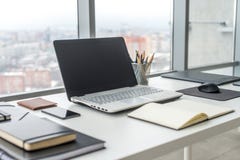 Werkplaats met notitieboekjelaptop Comfortabele het werklijst in van de bureauvensters en stad mening royalty-vrije stock foto Werkplaats met notitieboekjelaptop Comfortabele het werklijst in van de bureauvensters en stad mening royalty-vrije stock foto