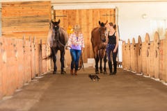Cowgirl and jockey walking with horses in stable Stock Photography Cowgirl and jockey walking with horses in stable Stock Photography
