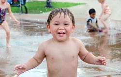 Wet little boy in urban splash pad